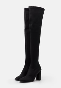 Bottes noires montantes jusqu'aux cuisses avec des pointes et des talons blocs hauts, fabriquées en tissu lisse et extensible.