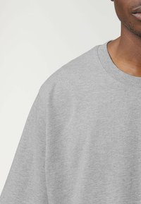 T-shirt grigio in cotone con scollo rotondo e maniche corte, caratterizzato da una texture liscia e un design a vestibilità comoda.