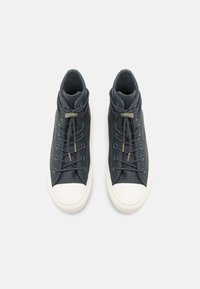 Zapatillas altas de cuero azul oscuro, con una puntera redondeada de goma blanca, cordones en contraste y un cuello de tobillo texturizado.