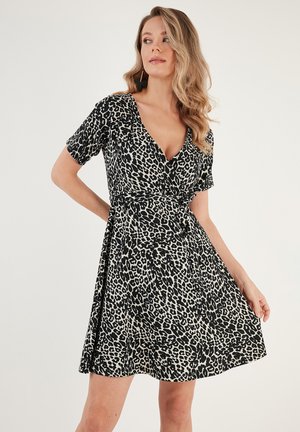 Robe léopard noire et beige avec un décolleté en V, des manches courtes, une taille élastique et une jupe fluide, fabriquée dans un tissu léger.