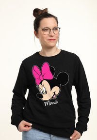 Felpa nera con grande grafica di un personaggio dei cartoni animati con un fiocco rosa, con il testo "Minnie" sotto. Materiale in cotone, design casual.