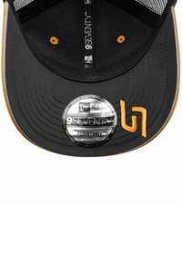 Czarna regulowana czapka baseballowa z płaskim daszkiem, ozdobiona pomarańczowymi akcentami i przeszyciami. Zawiera okrągłą metkę z logo z przodu.