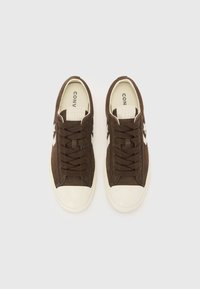 Sneaker in suede marrone con dettagli bianchi, punta rotonda e lacci piatti. Caratterizzate da suola in gomma e logo del brand sulla linguetta. Materiale testurizzato.