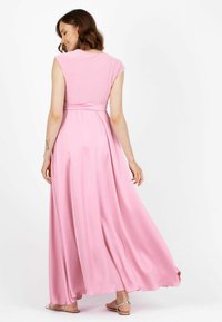 Abito lungo rosa realizzato in tessuto morbido, con maniche a cappuccio, vita adatta con una fascia e gonna fluente che scende fino a terra.