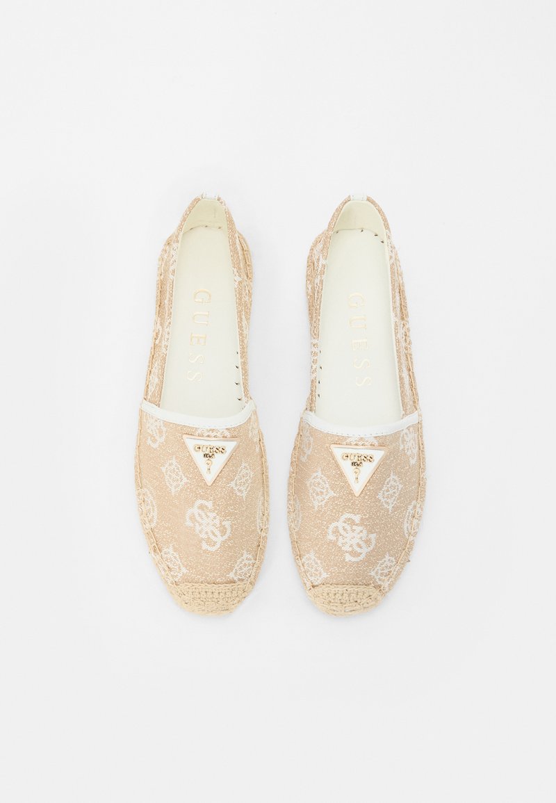 Beige Espadrilles mit einem Obermaterial aus Canvas, das ein dezentes Logomuster aufweist, weißen Akzenten und einem goldfarbenen Markenakzent auf der Vorderseite.