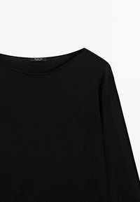 Maglietta nera a maniche lunghe con scollatura ampia, decorata con un'etichetta che recita "Massimo Dutti." Stilizzata su uno sfondo bianco semplice.