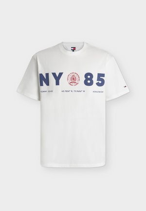 Biała koszulka z krótkim rękawem z granatowym napisem "NY 85", czerwonym okrągłym logo i tekstem zawierającym "Tommy Jeans", współrzędne oraz "Worldwide."