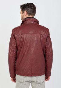 Bordeauxrotete Lederjacke mit hohem Kragen, gesteppten Schulterakzenten und einer glatten Textur. Das Design hat eine taillierte Silhouette und flache Nähte.