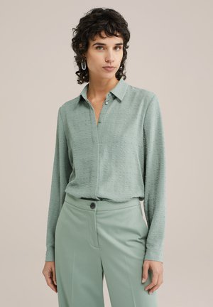 Langsleeve, overhemd met kraag in lichtgroen, met een gestructureerde stof met kleine patronen. Gepaard met bijpassende lichtgroene broek en een knoopdetails.
