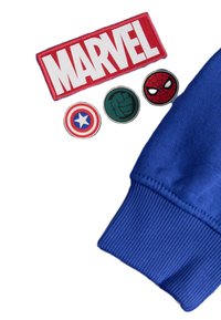 Patch ricamato rosso con la scritta "MARVEL", quattro patch circolari dei personaggi: lo scudo di Captain America, il pugno di Hulk e il volto di Spider-Man. Polsino in tessuto blu.