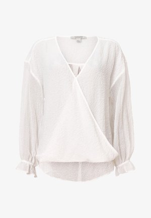 Valkoinen, kevyt tunika, jossa on rypistynyt pinta, V-pääntie ja kietaisuosa. Ominaisuuksiin kuuluvat pitkät, koottavat hihat, joissa on solmimisaksentit ranteissa.