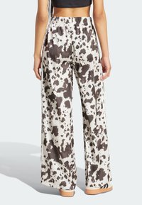 Vidbenta byxor med ett svart och vitt koskinnsmönster, tillverkade av ett slätt tyg med resår i midjan.