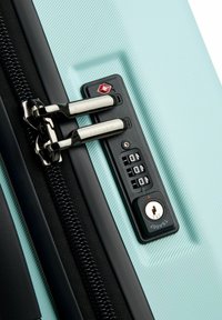 Valigia rigida di colore verde menta con strisce orizzontali, dotata di doppie cerniere, un lucchetto a combinazione nero e un'entrata con chiave.