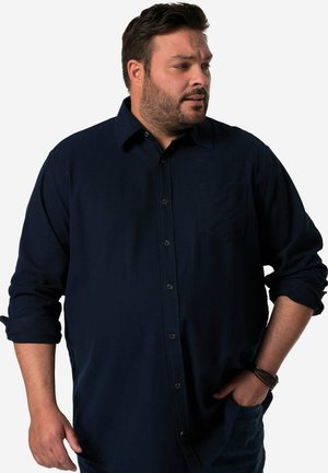 Marineblå skjorte med lange ærmer og knaplukning, der har en brystlomme, blød tekstur og opkrøllede ærmer. Udsmykket med mørke knapper.