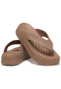 Infradito in gomma marrone con una fascia testurizzata, suola elevata e il nome del marchio "Crocs" impresso sul lato. Design spesso ed ergonomico.