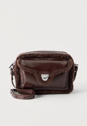 Mørkebrun læder crossbody-taske med blød lammeuldskant, forreste klaplomme med sølvspænde og justerbar skulderrem.