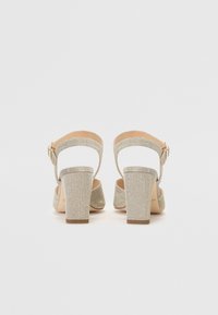Beige glitrende sandaler med høye hæler, bred blokkhelt, åpen bakdel og ankelrem med en liten spenne for justerbar passform.