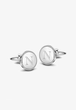 Srebrne spinki do mankietów z okrągłymi, białymi tarczkami z wygrawerowanym "N" i koralikowym wykończeniem. Gładkie wykończenie i polerowany metal.