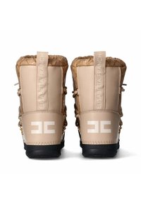 Stivali impermeabili beige con superiore imbottito, ganci per lacci e suola nera. Presentano il marchio sul retro e di lato in bianco.