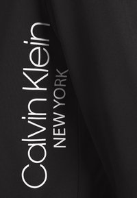 Tessuto nero con grandi lettere bianche che leggono "Calvin Klein NEW YORK", che presenta un design elegante e moderno.