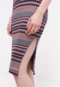 Koftklänning med vertikala flerfärgade ränder i vinröd, marinblå och grå. Har en sidoklyvning och ribbad textur.