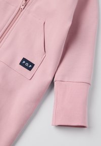 Helle rosa Zip-Hoodie mit Reißverschluss, Ärmel und Tasche mit navyblauem P.O.P.-Label auf der Tasche, präsentiert auf einem weißen Hintergrund.