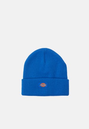 Gorro de punto azul con textura acanalada y un dobladillo. Presenta un pequeño parche rectangular con un diseño colorido.