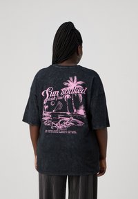 MustHave suuruses must T-särk, millel on roosa graafiline kujundus пальмide, lamamistoolide ja tekstiga "Sun Soaked Splash Fan" seljal.