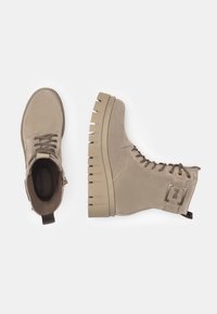 Bottines en suède beige avec un col rembourré, bout rond et semelle en caoutchouc épaisse présentant des rainures horizontales. Design à lacets avec détail de logo.