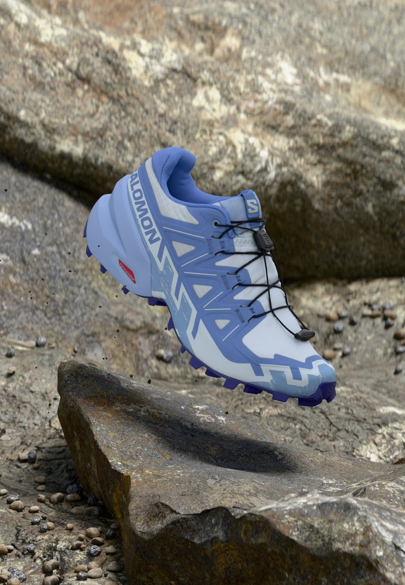 Ανοιχτό μπλε παπούτσι για τρέξιμο με ενισχυμένο επάνω μέρος από δίχτυ, μαύρα κορδόνια και εξωτερική σόλα με βαθύ πέλμα για καλύτερη πρόσφυση. Διαθέτει λογότυπο και γωνιώδη διακοσμητικά στοιχεία.