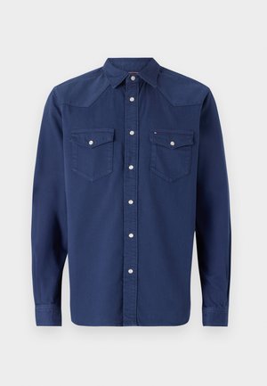 Donkerblauw overhemd met lange mouwen en een button-down kraag, twee borstzakken en zilveren hardware. Gemaakt van een gladde stof.