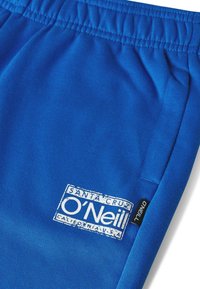 Blauwe joggingbroek in zachte, gestructureerde stof met een elastische tailleband. Voorzien van een wit logo en labeldetails ter herkenning van het merk.