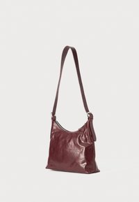Borsa a spalla in pelle bordeaux con una texture liscia, tracolla regolabile e dettagli in metallo argentato. Design semplice e curvato.