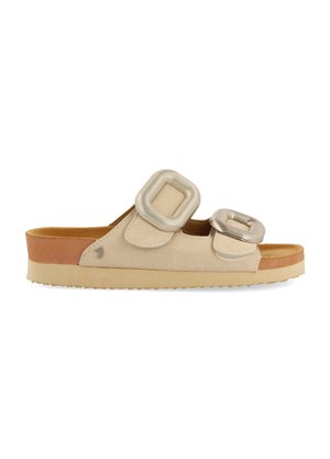 Sandalia de tacón beige que presenta dos correas con hebillas metálicas cuadradas, parte superior suave similar a gamuza, plantilla en tono marrón y suela de goma texturizada.