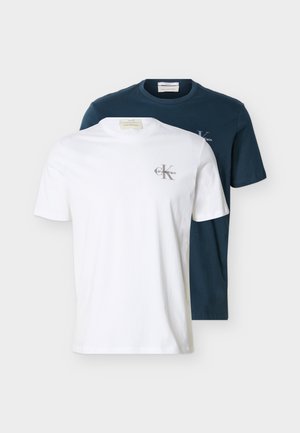 Deux t-shirts Calvin Klein à manches courtes et col ras du cou, un blanc et un bleu marine, avec de petits logos sur la poitrine gauche.