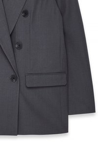 Blazer grigio doppiopetto realizzato in tessuto testurizzato, caratterizzato da quattro bottoni neri e una tasca singola sul lato sinistro.