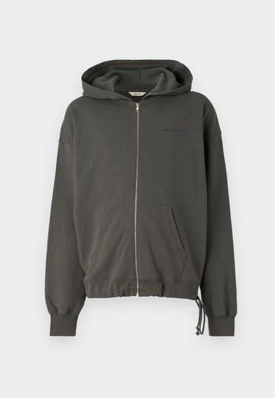 Tamsiai pilkas užtrauktukas megztinis, pagamintas iš fliso medžiagos, turintis priekinę kišenę, raištelio apvados ir subtilų prekės ženklą kairėje krūtinės pusėje.