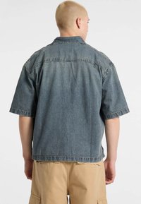 Korte mouwen, blauwe denim overhemd met een relaxte pasvorm, kraag en zichtbare stikseldetails op de achterkant en mouwen. Geen zichtbare zakken.
