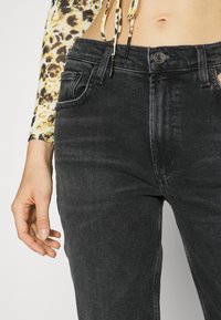 Svarta denimjeans med en figurnära design, subtil textur, femficksstil och knappstängning i midjan.