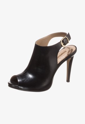 Zapato de tacón alto negro de cuero con puntera abierta, textura suave, correa ajustable y detalle de hebilla dorada.