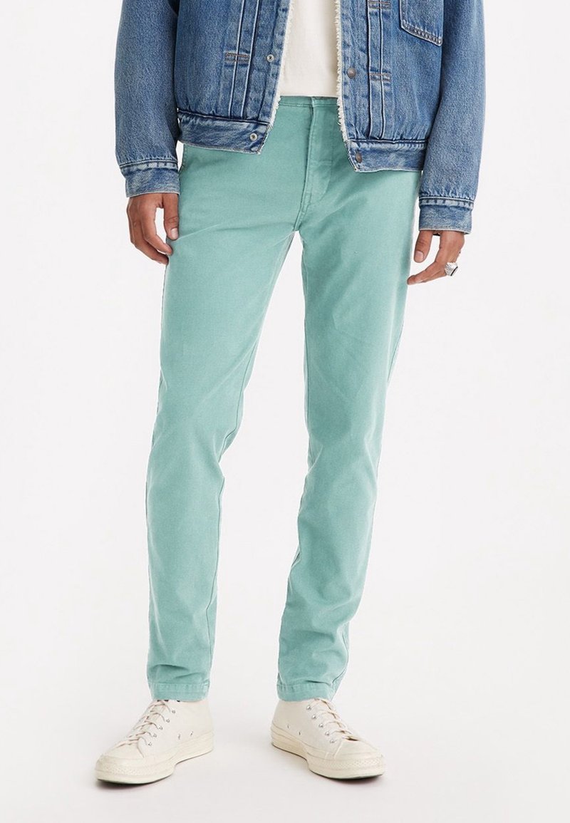 Ljus teal, slim-fit byxor i bomull med en slät textur. Tillsammans med en denimjacka och vita högskaftade sneakers.