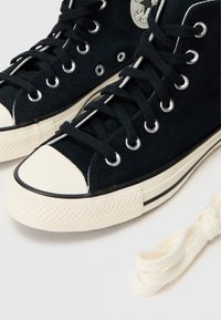 Μαύρα αθλητικά παπούτσια ψηλού κορμού από σουέτ με λευκή λαστιχένια κάπα στη μύτη, αντίθετη λ�ευκή μεσαία σόλα, ασημένιες θηλιές και μαύρα κορδόνια. Περιλαμβάνονται επιπλέον κορδόνια.