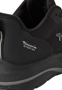 Scarpe da ginnastica nere con tomaia liscia in materiale sintetico, dettagli testurizzati, branding prominente e design della suola ammortizzata per il comfort.