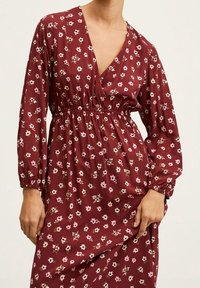 Kaštanové květinové šaty s dlouhými nařasenými rukávy, výstřihem do V, římským pasem a řaseným detailem; po celé ploše zdobené malými bílými a růžovými květinami.