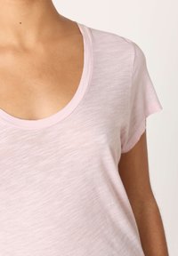 Svetlo roza kratka majica s kratkimi rokavi in okroglim izrezom, izdelana iz mehke, rahlo teksturirane tkanine. Prijeten sproščen kroj z zavihanimi rokavi.