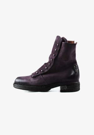 Bottine en daim violet foncé avec des boutons décoratifs sur le devant et un talon empilé noir ainsi qu'une semelle assortie.