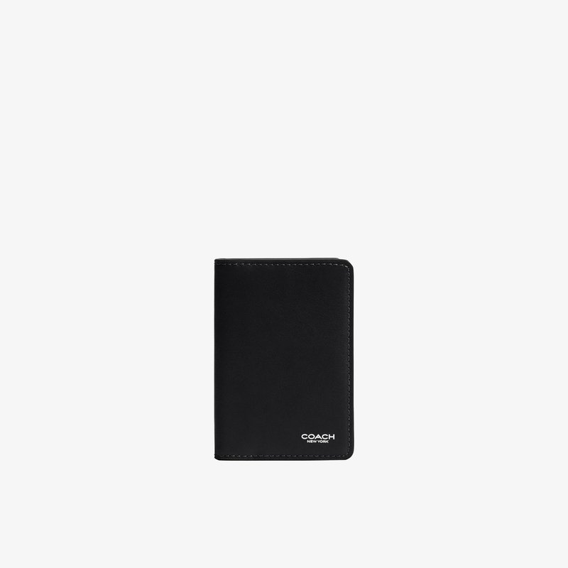 Portefeuille Coach en cuir noir avec logo blanc embossé dans le coin inférieur droit sur fond blanc uni.