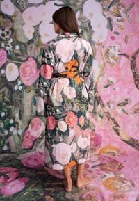 Badjas met bloemenpatroon in een kleurenpalet van roze en groen; gemaakt van gestructureerde stof, met lange mouwen, een ceintuur en een knie-lange snit.