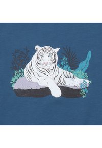 Illustration eines weißen Tigers auf blauer Stoffoberfläche. Der Tiger liegt auf einem Felsen, umgeben von türkisfarbenem Laub, mit detaillierten Streifen und blauen Augen.