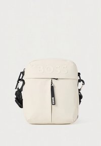 Hvid crossbody taske med præget "BOSS" logo, frontlomme med lynlås, justerbar rem og glat, holdbart stof. Sorte detaljer og hardware.
